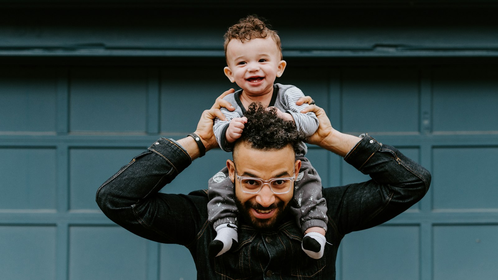 A smiling dad with his laughing baby on his shoulders