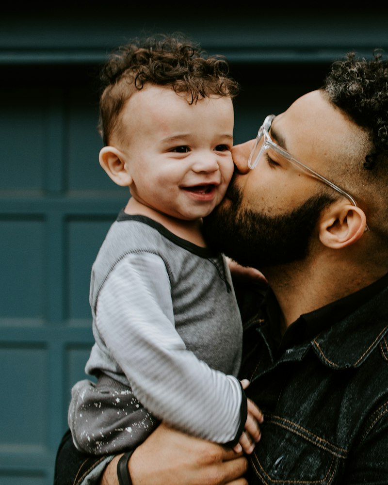 A dad kissing his smiling baby