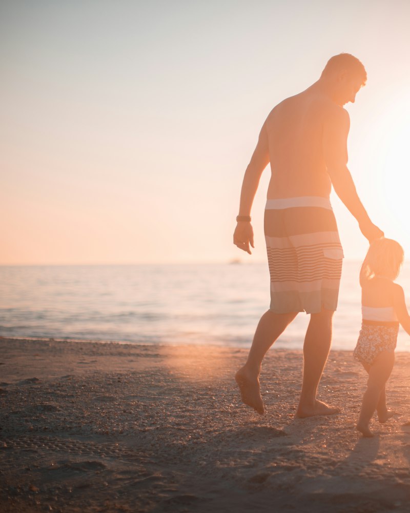 A dad carrying his daughter toward the sea